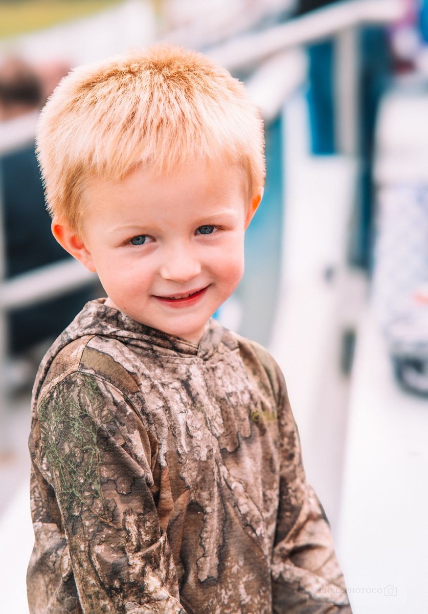 Young boy in a camo hoodie smiling at the camera
