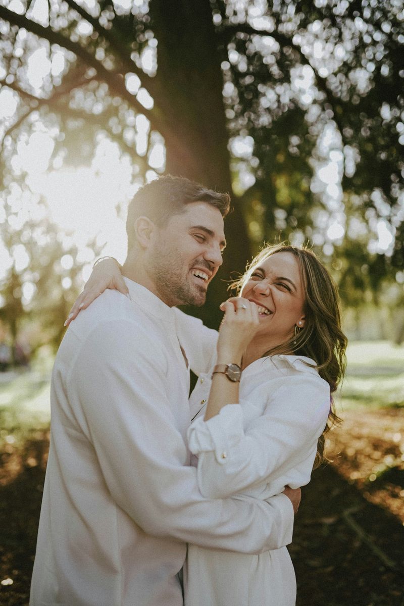 Couple embracing and laughing under trees in golden light