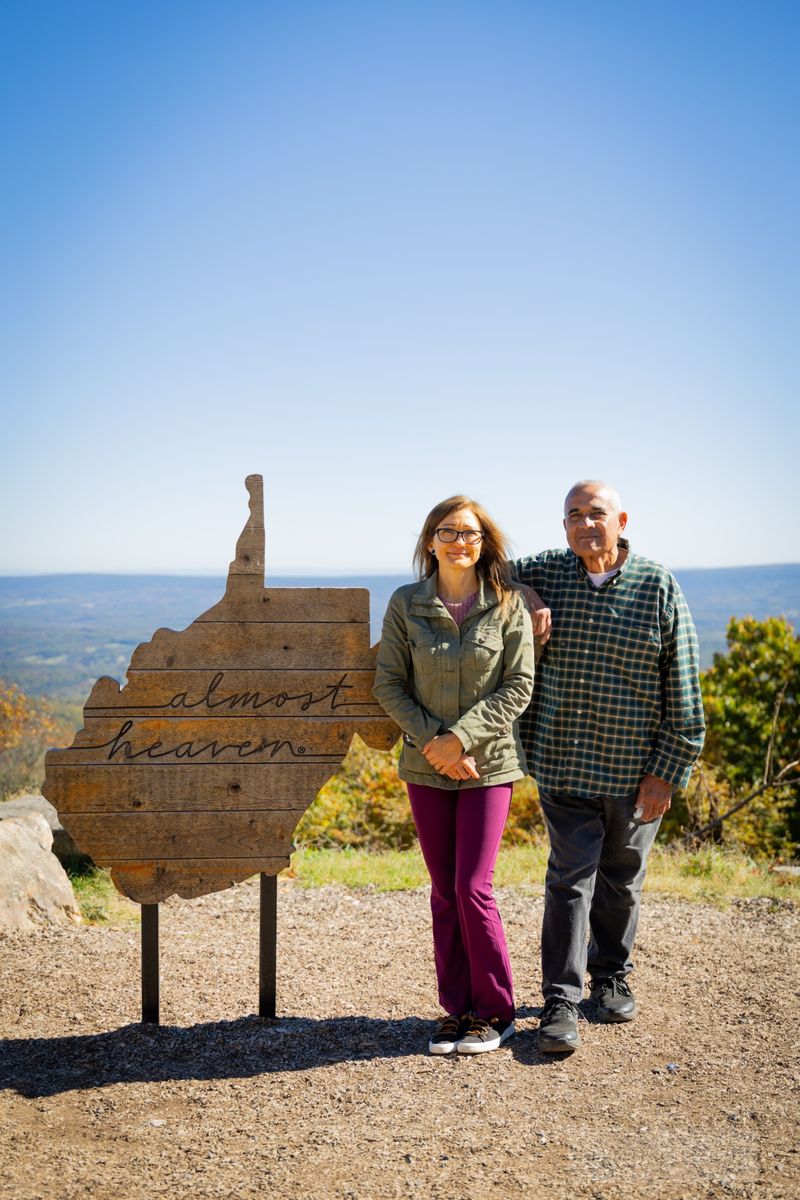 Couple standing beside an overlook sign with a mountain view